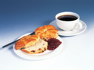 baked bread on the plate beside coffee in the teacup