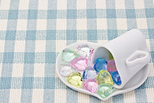 white ceramic mug on heart shaped ceramic saucer filled with assorted color stones