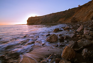 time lapse photography of ocean wave surrounded of rocks under sunset HD wallpaper