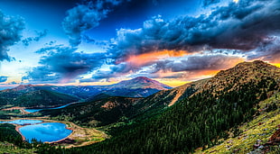 body of water surrounded with mountains and trees