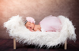 baby in pink tutu skirt sleeping on white fur mat close-up photo HD wallpaper