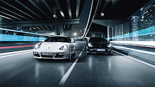 two grey and black car passing on road with buildings nearby