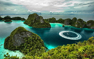 rock formations on calm water under white clouds and blue sky