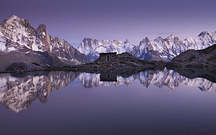 brown concrete house near body of water with mountain range background during daytime