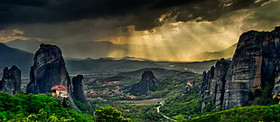 grey rock formation surrounded by green leaf trees under grey sky photography, meteora