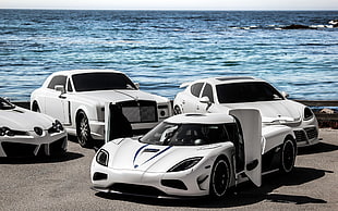 photo of four white cars near sea