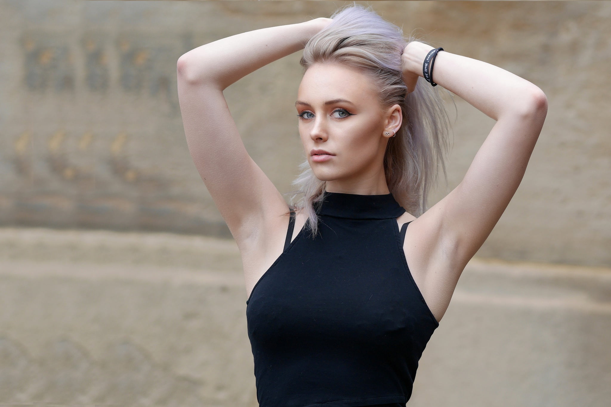 woman in grecian neck top with two hands holding her hair up