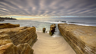 brown rock formation near body of water under white skies, nature, landscape, water, rock