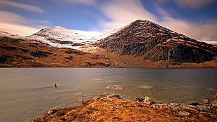 body of water beside brown mountain