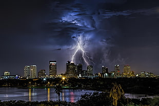 white lightning under blue and black clouds over black and brown buildings HD wallpaper