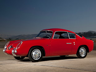 red vintage coupe on brown asphalt road