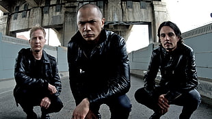 three men wearing black leather jackets squatting on gray concrete pavement HD wallpaper