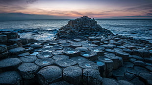 piled stone beside body of water