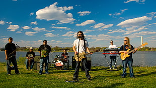 man in white shirt singer with his band performing under clear sky