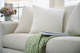 white book beside white throw pillow