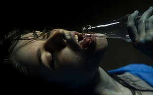 woman wearing blue top drinking glass of bottle