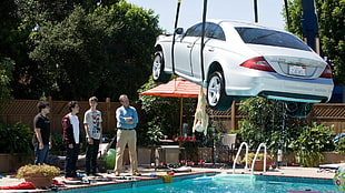 white car being pulled up from pool during daytime