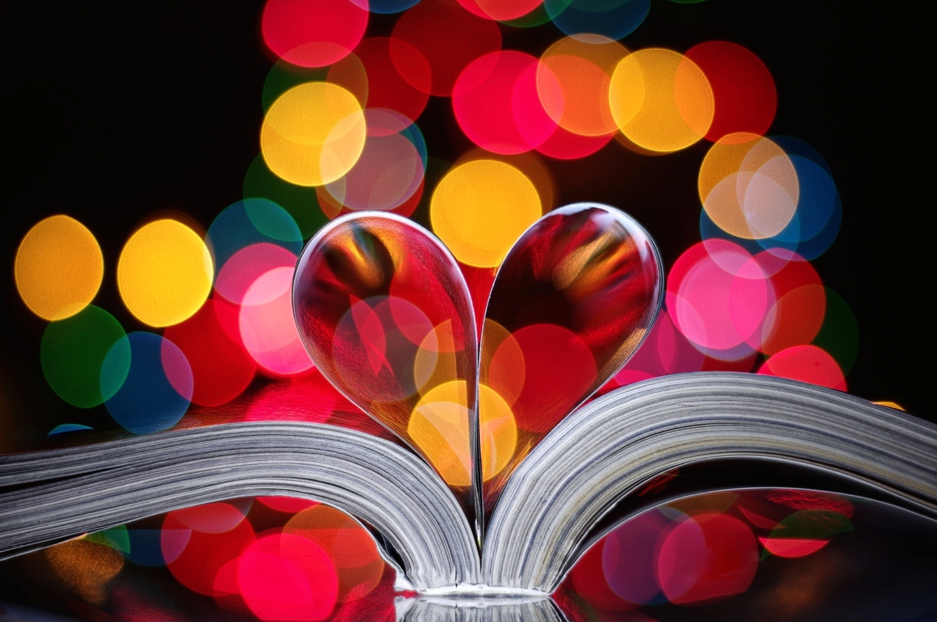 two book pages shaped into heart with bokeh light background