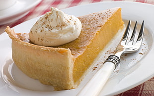 slice of pie with white cream toppings on white plate with spoon