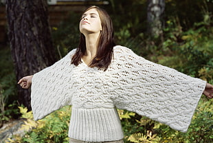 woman wearing knitted dress and spread her arms surrounded by plants