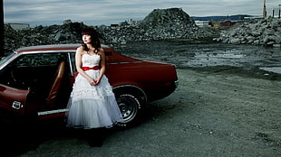 woman wearing white wedding dress near red car