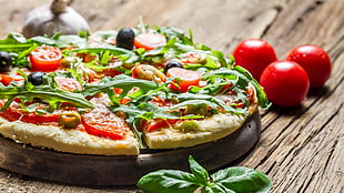 Pizza on brown wooden tray near three red tomatoes HD wallpaper