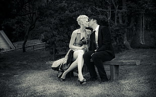 man and woman kissing while sitting on bench