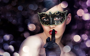woman wearing black and brown masquerade and black gloves pointing her index finger near her lips
