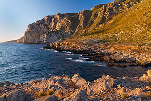 brown mountain near body of water during daytime HD wallpaper