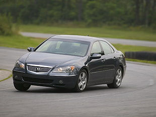 black Acura sedan on road near grass field