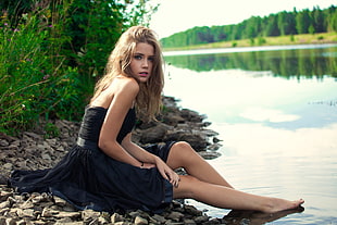 woman in black dress sitting beside body of water HD wallpaper