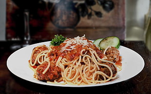 spaghetti with sauce and meatballs on top of round white plate HD wallpaper