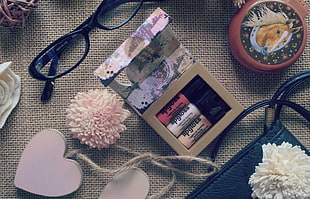 nail polish beside eyeglasses and bag ornament