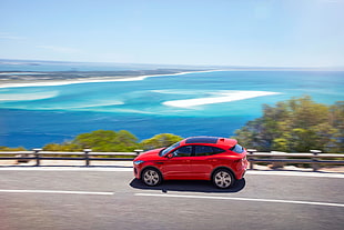 red SUV on road with overlooking of ocean HD wallpaper