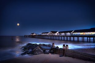 time lapse photography of black rocks on body of water near houses, southwold