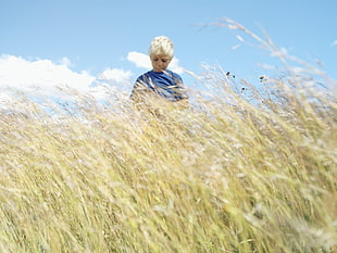 boy standing in the middle of grassland HD wallpaper