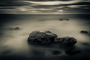 grayscale photography of stones on sea HD wallpaper