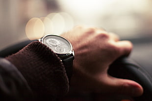 person left arm wearing silver round chronograph watch with black band