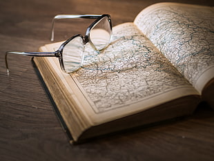 black framed eyeglasses on top of book