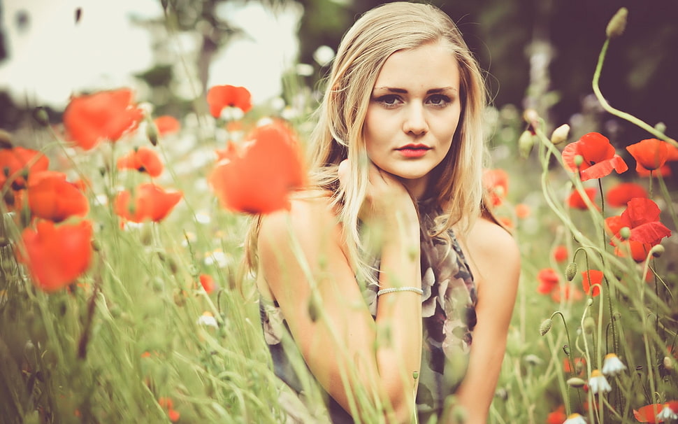 selective landscape photography of woman wearing gray ruffled sleeveless top standing between red petaled rose plants HD wallpaper