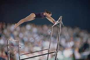 selective focus photography of gymnast woman hang on bar