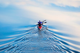 two person in red kayak on body of water during daytime